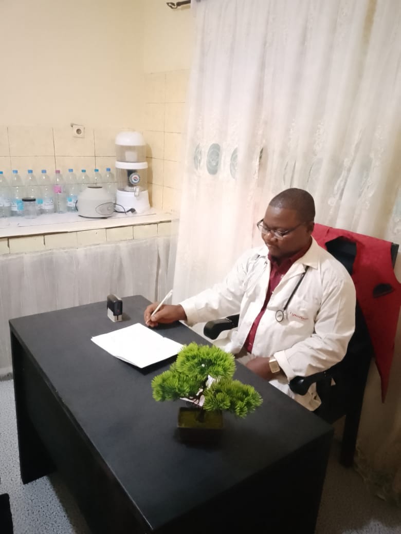 Dr. Jum Bernard writing patient case notes at his consultation desk