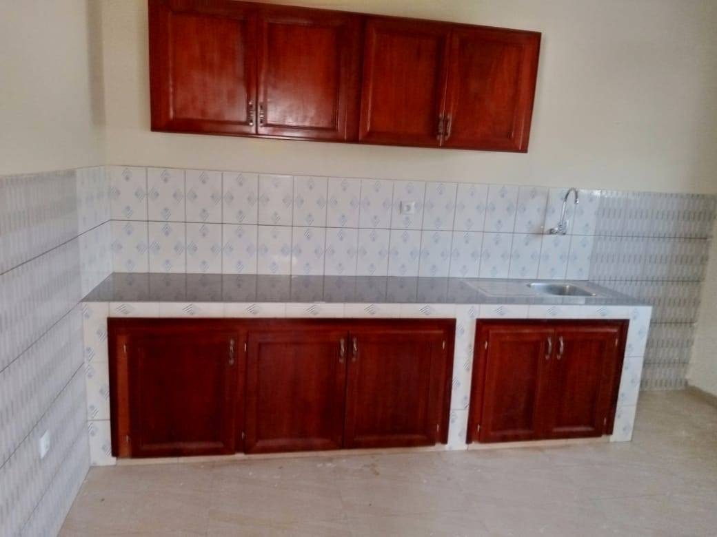 Fitted kitchen with wood cabinetry, tiled splashback and stainless sink